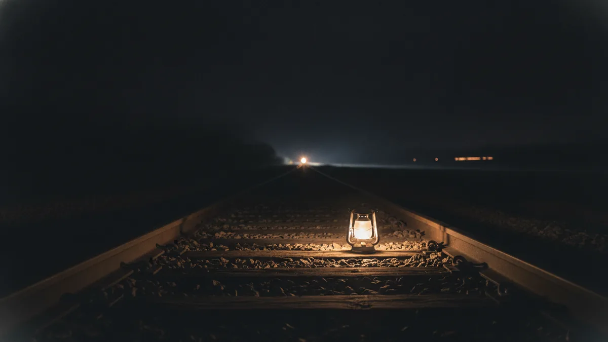 Waiting, love, and heartbreak Lantern-lit railroad tracks at night with distant lights suggesting waiting.